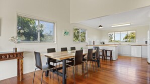 Une cuisine moderne avec des meubles blancs, une table à manger en bois et des chaises noires.