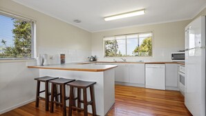 Une cuisine moderne avec un îlot central en bois, des meubles blancs et un lave-vaisselle.