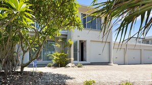 Un edificio moderno con un basculante, vialetto lastricato e vegetazione tropicale.