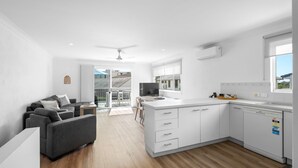 Una cucina moderna con mobili bianchi, lavastoviglie integrata e finestra con vista sul balcone.