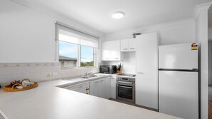 A modern kitchen with white cabinets, a built-in oven, a microwave, and a refrigerator. - Blairgowrie 4 Peregian Beach (PEREGIAN BEACH)