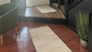 Un intérieur moderne avec un escalier, un fauteuil vert, une porte blanche et un luminaire suspendu.