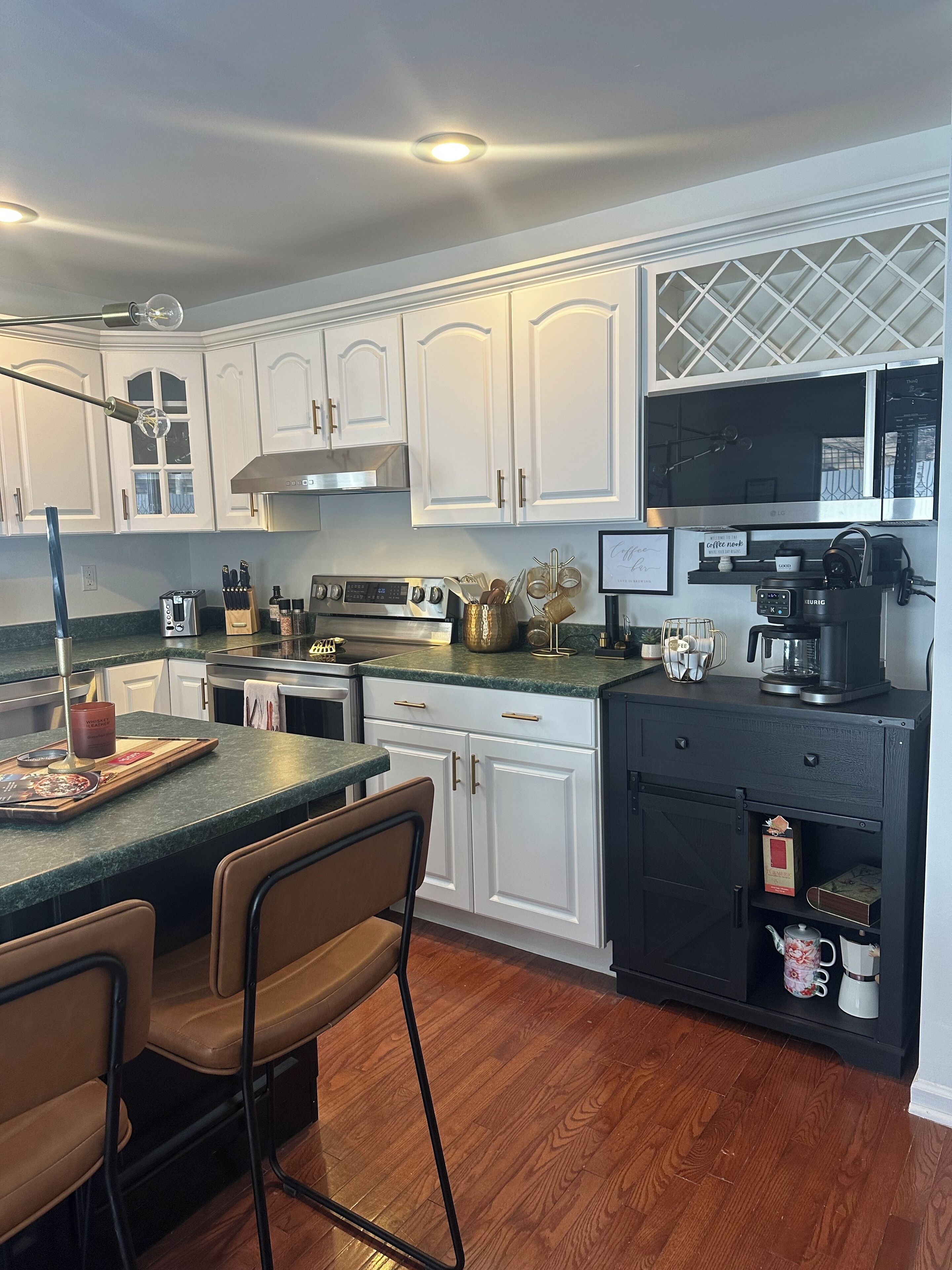 A modern kitchen with white cabinets, a black countertop, and a wooden floor.