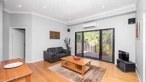 A modern living room with a wooden dining table, a sofa, and a TV. - 40 Jacana Street, Peregian Beach  - Recent Improvements (PEREGIAN BEACH)