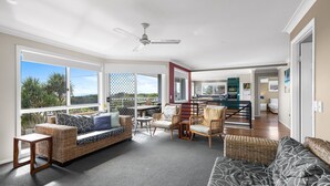 A spacious living area with a sofa, chairs, a dining table, and a kitchen in the background. - Brolga Place Noosa Shire (PEREGIAN BEACH)