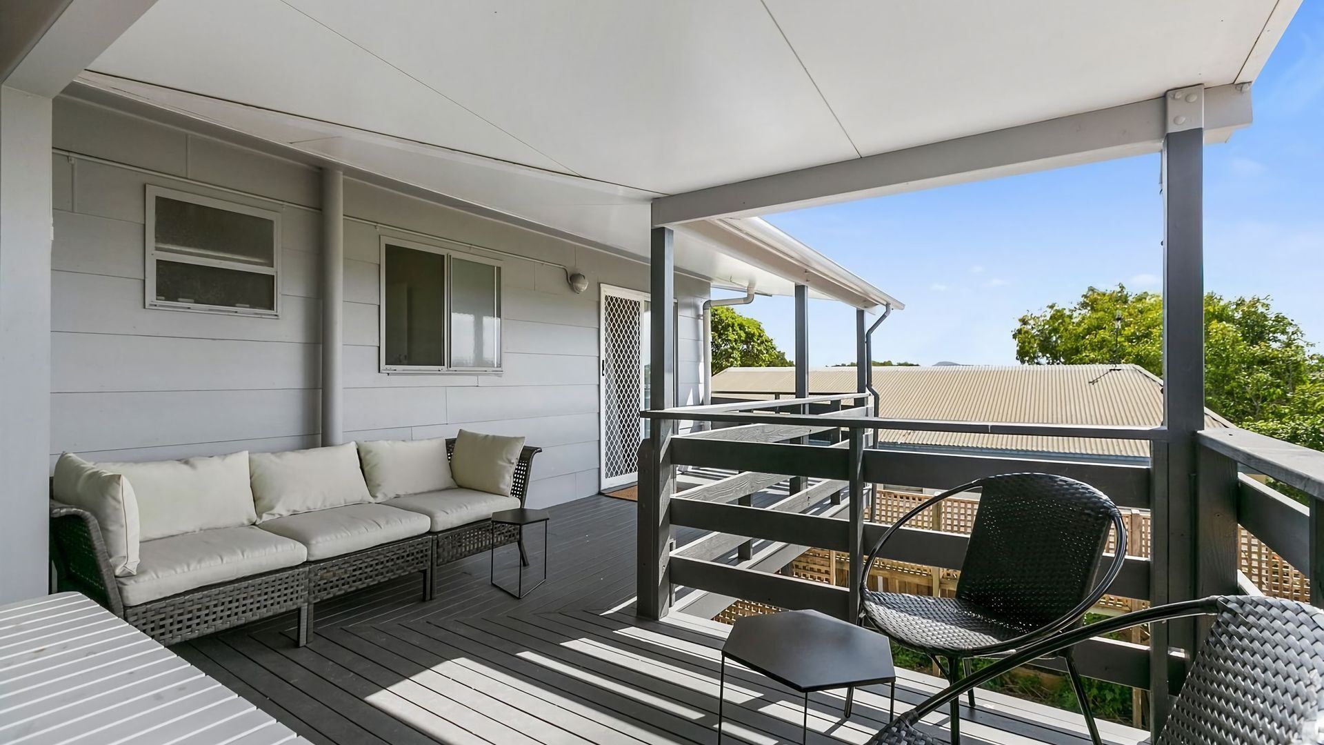 A covered outdoor area with a sofa, chairs, and a table.