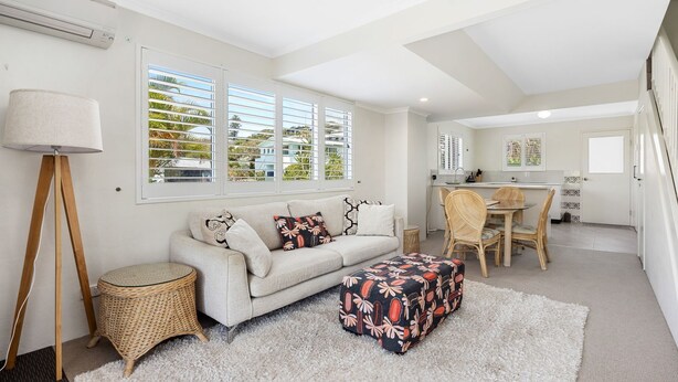 A modern living room with a sofa, ottoman, and dining area. - Blairgowrie 5 Peregian Beach (PEREGIAN BEACH)