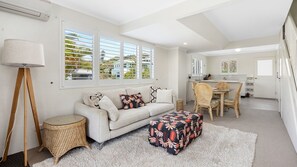 Una sala de estar moderna con sofá, reposapiés y zona de comedor.