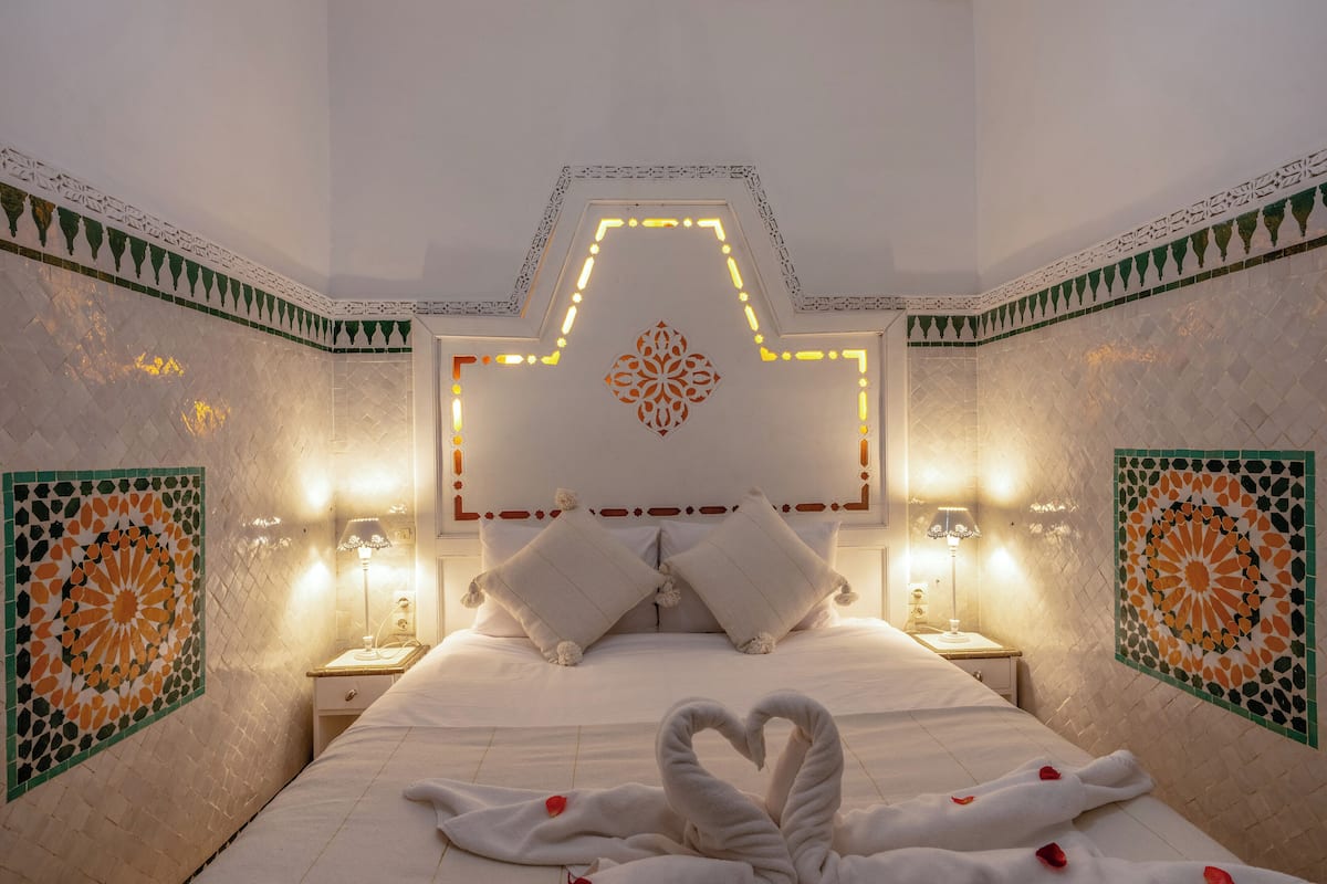 Una habitación de hotel con una cama, dos mesitas de noche y azulejos decorativos en la pared.