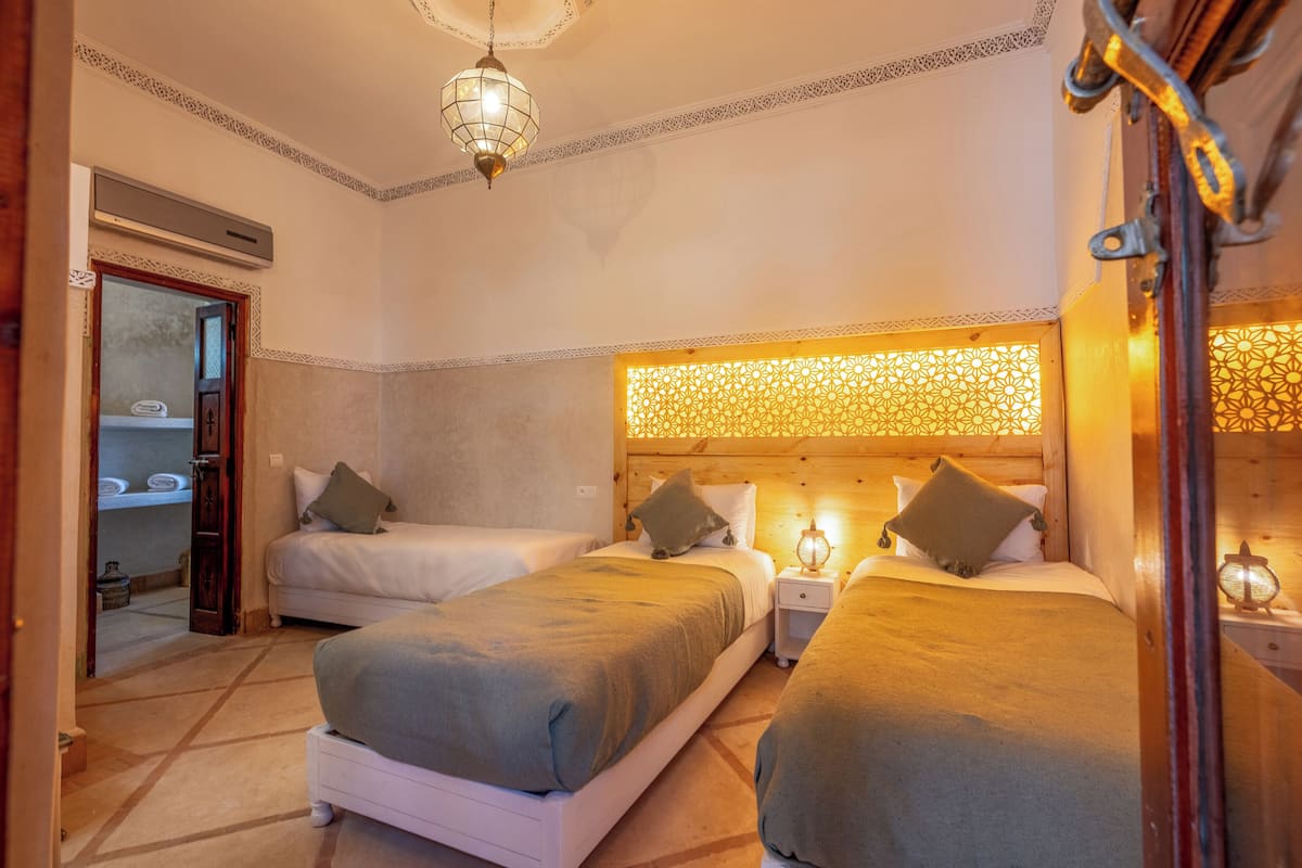 Una habitación con dos camas, cabecero de madera, lámparas de noche y un panel decorativo en la pared.
