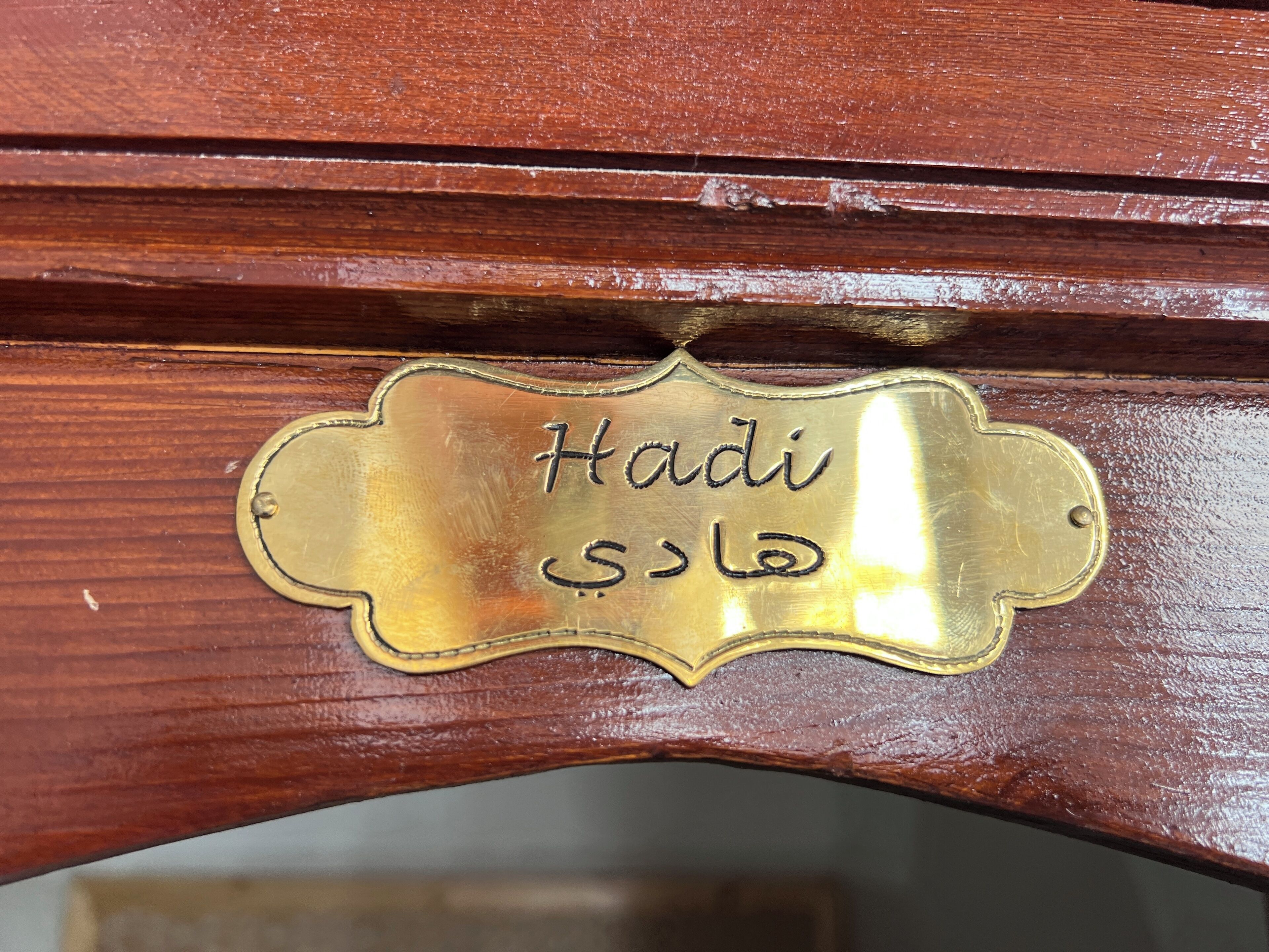 A brass nameplate with the name "Hadi" and Arabic script.
