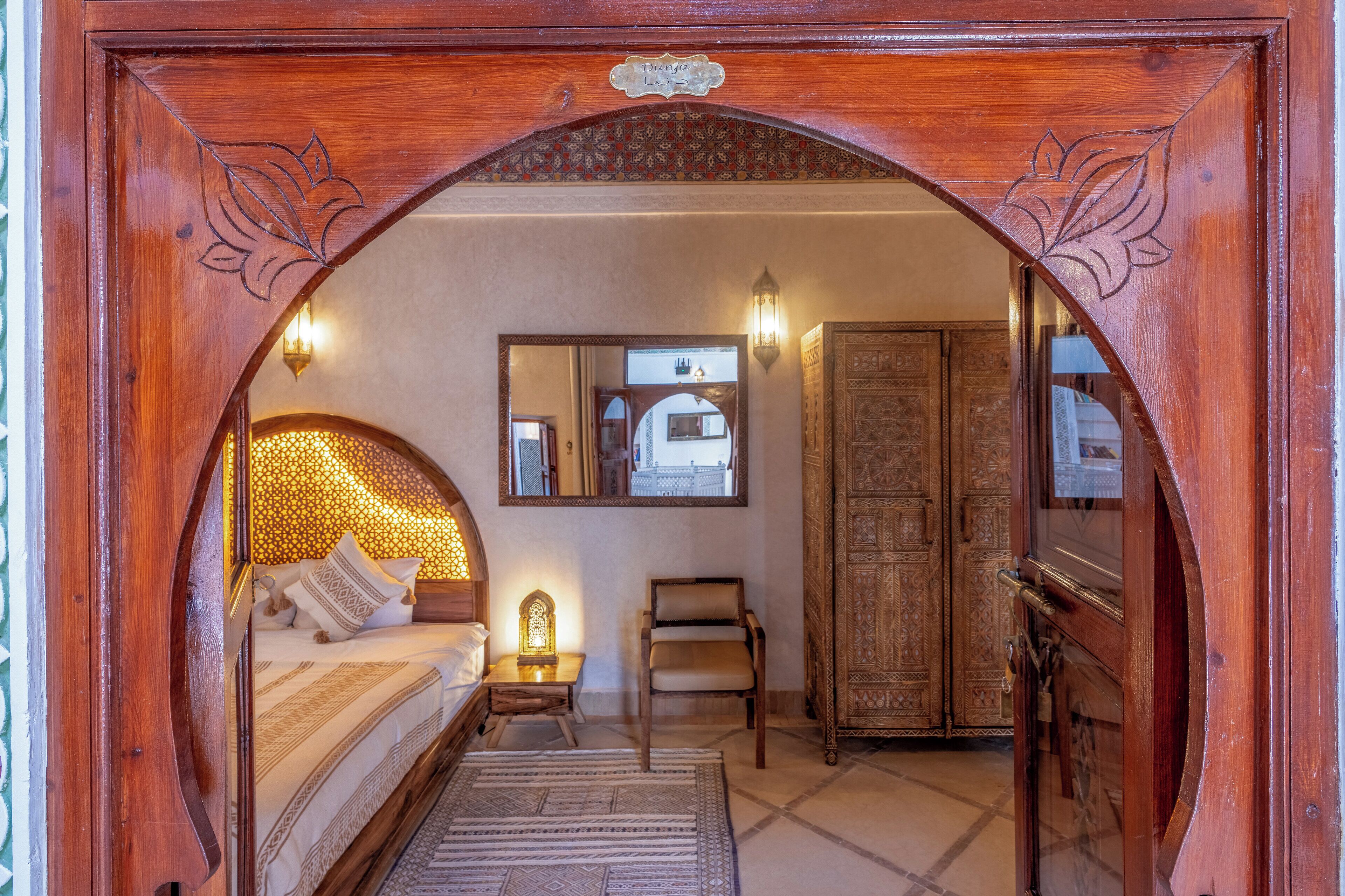 A room with a bed, a chair, a wardrobe, and a mirror.