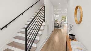 A modern interior with a staircase, wooden flooring, and a dining area with natural light.