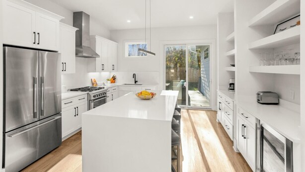 A modern kitchen with white cabinetry, stainless steel appliances, and a central island.