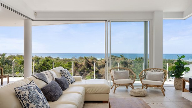 Ein modernes Wohnzimmer mit einem großen Fenster und Blick auf eine Küstenlandschaft.