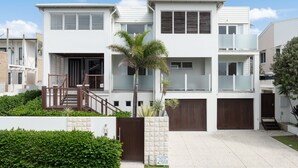 A modern two-story house with a covered driveway, a wooden staircase, and a small garden with a palm tree. - Sea Splash Peregian Beach (PEREGIAN BEACH)