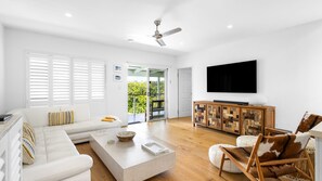 A modern living room with a sofa, coffee table, and a TV mounted on the wall. - Tranquil Haven Peregian Beach (PEREGIAN BEACH)