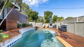A backyard with a swimming pool, wooden deck, and outdoor furniture. - Tranquil Haven Peregian Beach (PEREGIAN BEACH)