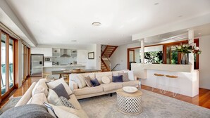 Ein modernes Wohnzimmer mit einer Couch, einem Couchtisch und einer Küche im Hintergrund.