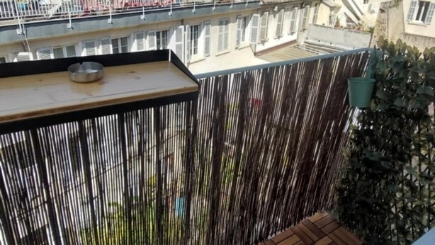 A rooftop terrace with a wooden floor, a metal railing, and a view of surrounding buildings. - Bright apartment in the heart of the Old Port - calm, comfort & ideal location (Marseille)
