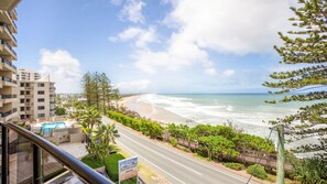Blick vom Balkon einer Wohnung auf einen Sandstrand und den Ozean.