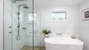 A modern bathroom with a glass-enclosed shower, a freestanding bathtub, a small window, and a potted plant. - Gannet's Nest Peregian Beach (Peregian Beach)