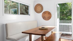 Una stanza con un tavolo di legno, una panca bianca e due cesti intrecciati appesi al muro.