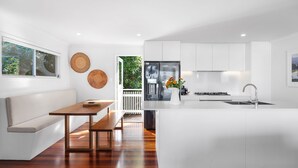 Una cucina moderna con mobili bianchi, una panca di legno e un tavolo da pranzo.