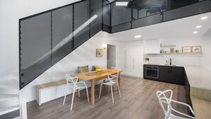 A modern kitchen with a wooden table and white chairs, a black oven, and a white countertop. - Martin's Patch Unit 2 Peregian Beach (Peregian Beach)