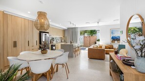 Uma cozinha moderna com uma ilha central, cadeiras brancas e uma luminária pendente.