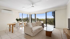 A spacious living room with a sofa, coffee table, and dining area. - First Avenue Glade 6 (Coolum Beach)