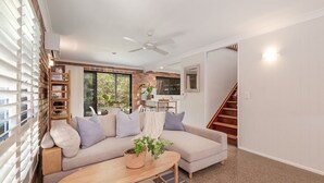 A modern living room with a sectional sofa, a wooden coffee table, and a staircase. - Ashton Villa 1 Peregian Beach (Peregian Beach)