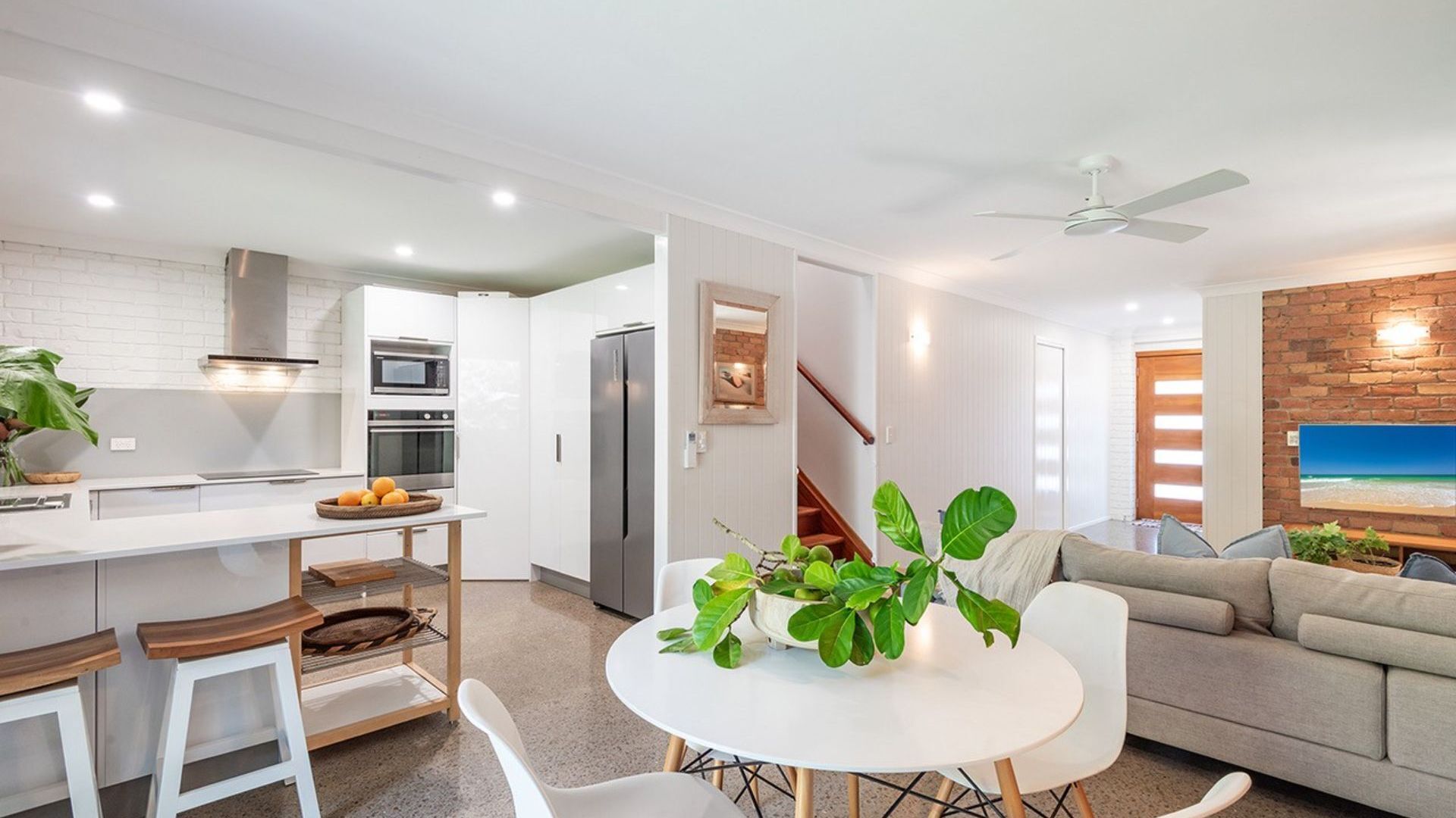 A modern kitchen with white cabinetry, a central island, and a dining area with a round table and chairs.