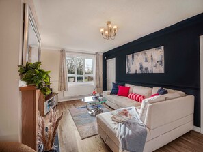 A living room with a beige sofa, a coffee table, a chandelier, and a large abstract painting on the wall. - 3BR Contractor-Ready Home • Parking • Middleton (Middleton)