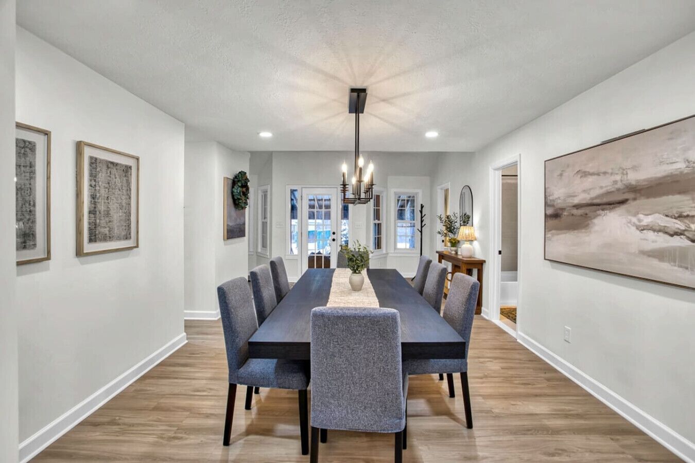 Une salle à manger spacieuse, avec une longue table, des chaises modernes et un lustre.