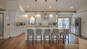 Une cuisine spacieuse dotée d’un grand îlot central, de meubles blancs et d’appareils électroménagers modernes.