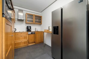 Eine moderne Küche mit Holzschränken, einem Edelstahlkühlschrank und einer Kaffeemaschine.