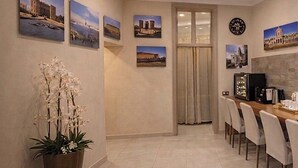 Ένας χώρος τραπεζαρίας με ένα μεγάλο τραπέζι, καρέκλες, ένα φυτό σε γλάστρα και πίνακες ζωγραφικής κρεμασμένους στον τοίχο.