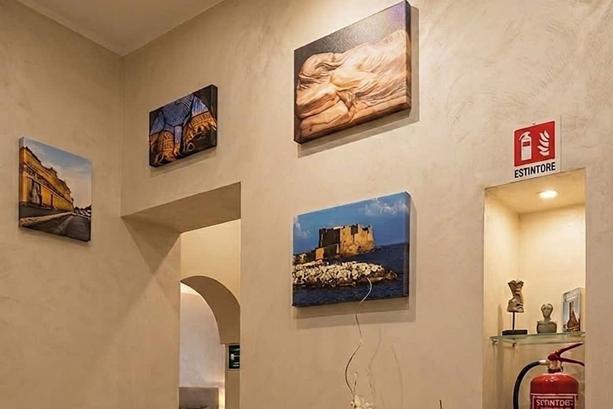 A hallway with artwork, a potted plant, and a fire extinguisher.