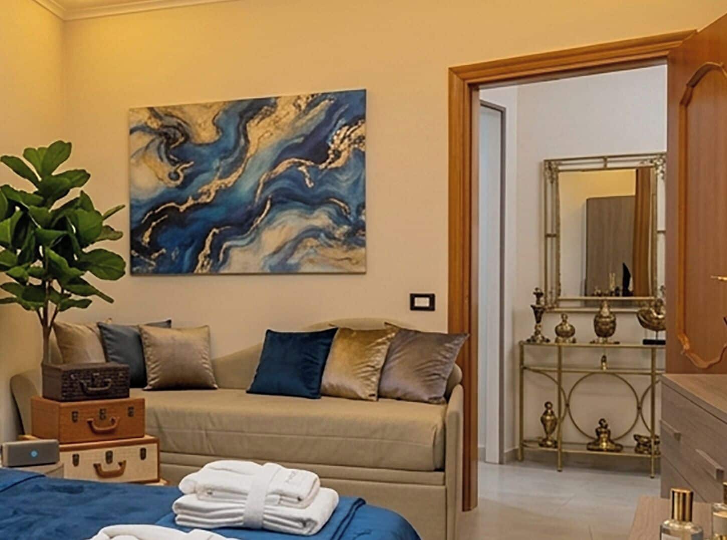 Ein Zimmer mit einer Couch, einem Gemälde, einer Pflanze und einem Konsolentisch mit Dekoration.