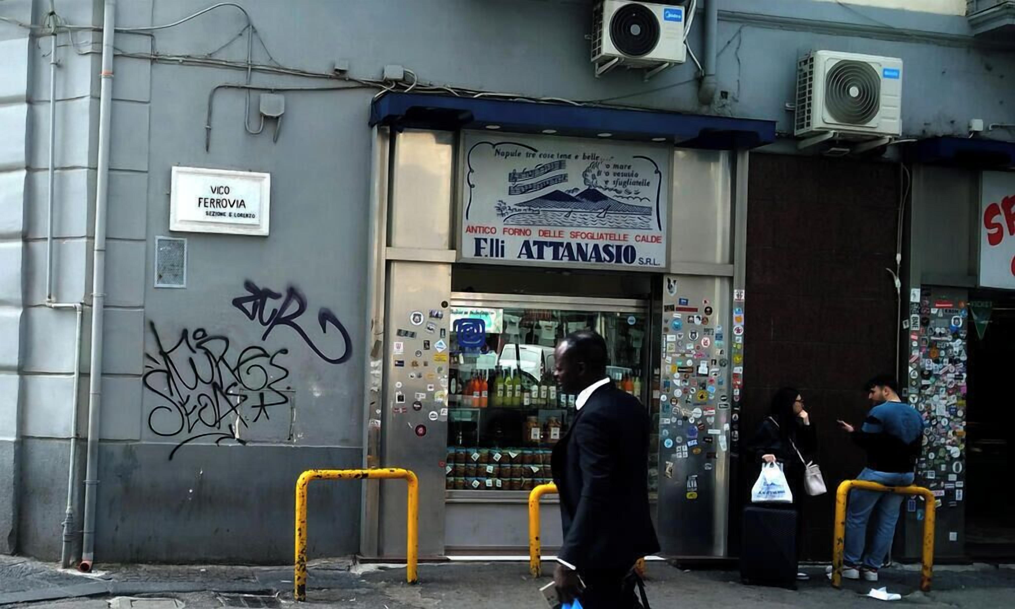 A storefront with a sign for 'Eli Attanasio S.R.L.' and a window displaying various products.