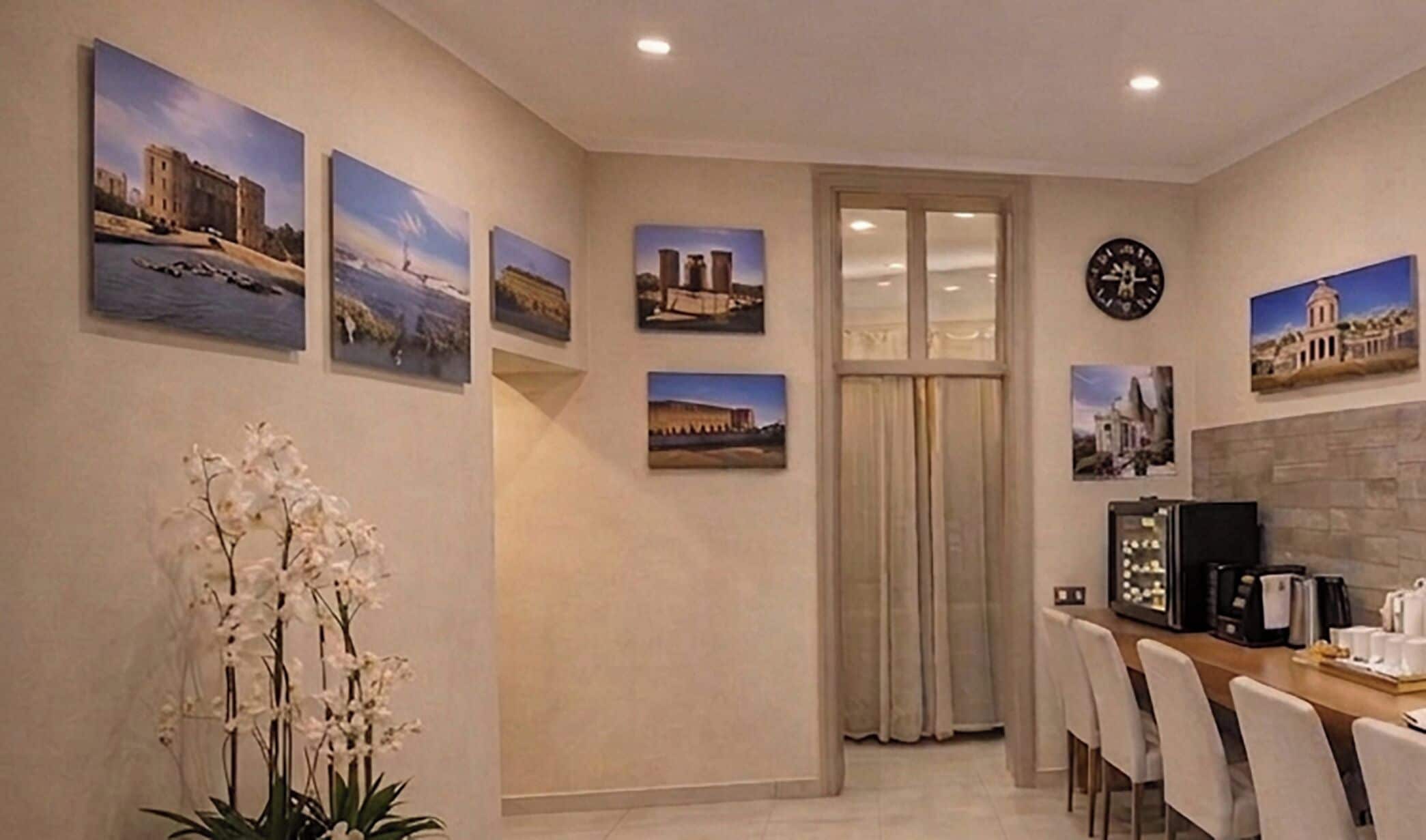 A dining area with a table, chairs, a coffee machine, and a clock on the wall.