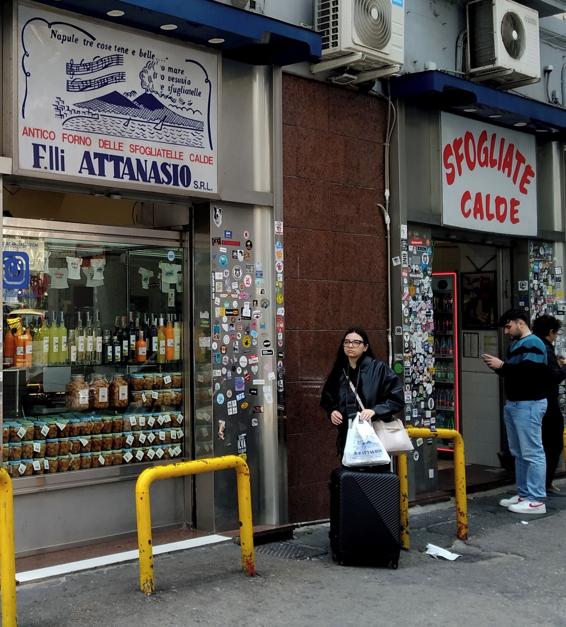 Egy üzletportál, amelyen egy „F.III Attanasio” feliratú tábla és egy másik, „Sogliante Calde” feliratú tábla látható.