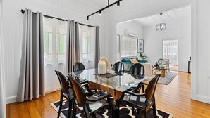 A spacious dining area with a glass table, black chairs, and a modern chandelier. - Wandal Haven • 3BR • King • + 2 Doubles • Pets OK (Rockhampton)