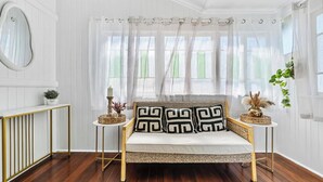 A cozy room with a white-framed sofa, a gold-framed console table, and a large mirror. - Wandal Haven • 3BR • King • + 2 Doubles • Pets OK (Rockhampton)
