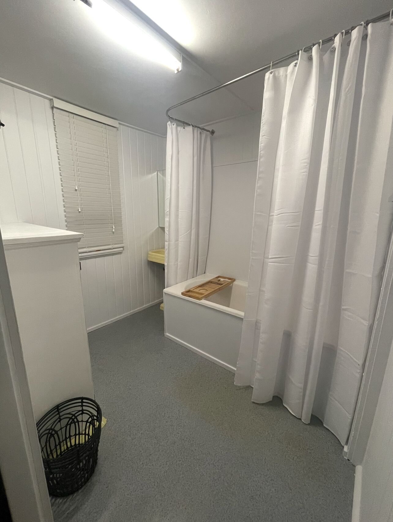 A small, clean bathroom with a shower, toilet, and a small shelf.
