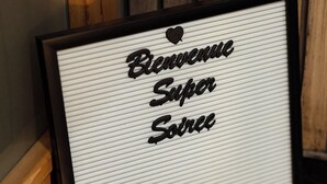 A framed sign with the words "Bienvenue Super Soirée Love" against a wooden background.