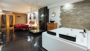 Een moderne badkamer met een groot, wit bad, een houten kast en een stenen muur.