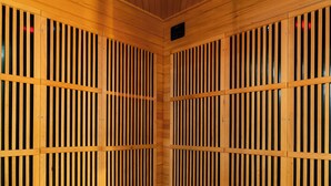 A sauna with wooden slatted walls and a wooden floor, featuring a ceiling with recessed lighting.