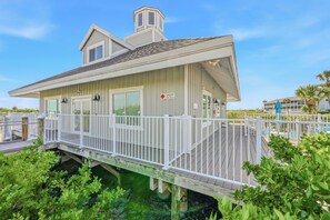 Ein Küstenhaus mit Terrasse, überdachter Veranda und Blick auf das Wasser.